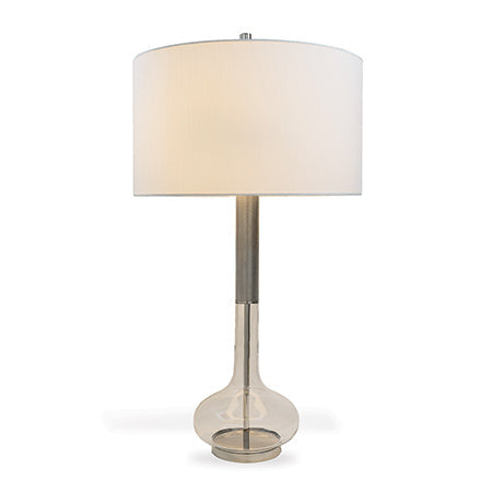 A mid century style lamp with a glass base and nickel finished knurled textured metal neck, topped with a cylinder shaped nickel finished metal finial and a white shade.