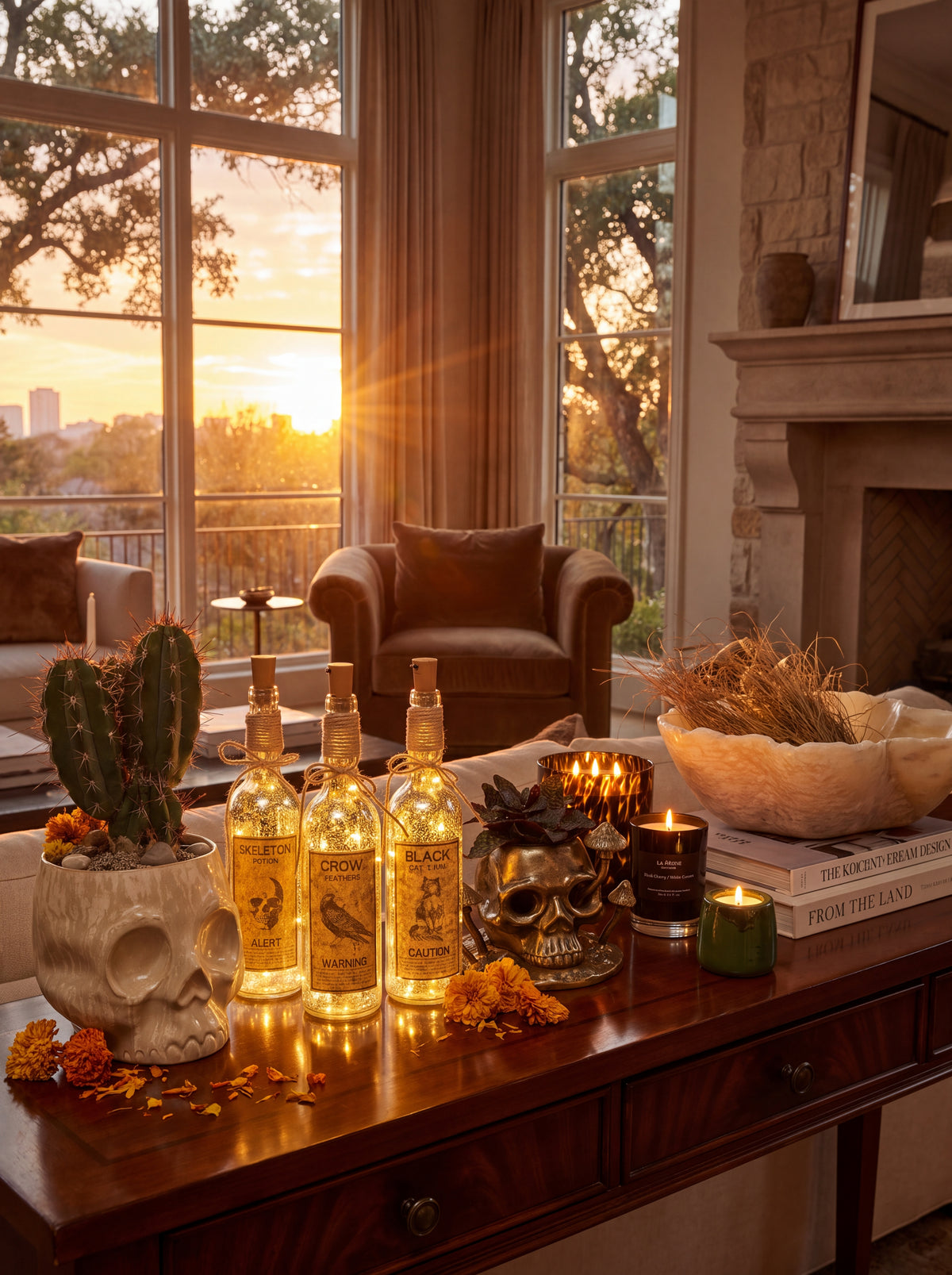 Four bottles of tequila displayed on a wooden console table in a warm, decorated living room at sunset. The bottles are styled with a skull planter cactus, candles, and books, with a fireplace and large windows in the background.