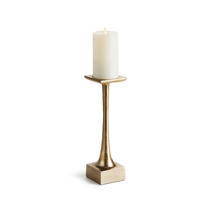A gold-colored metal candle stand with a weighted base and a tall slender body, designed to hold a pillar candle.
