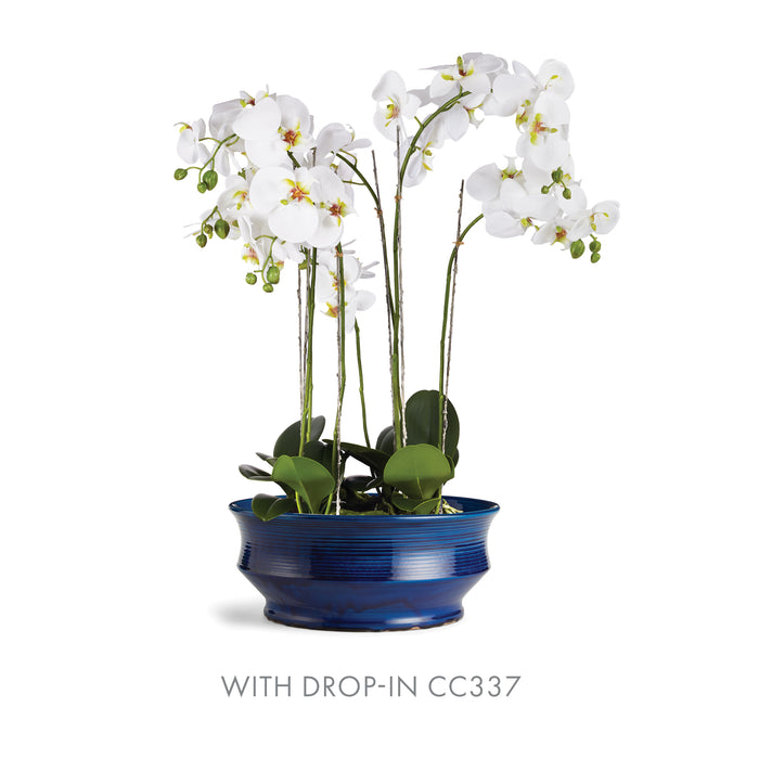 White orchid stems with green leaves in a cobalt blue ceramic decorative bowl, drop-in CC337 label visible.