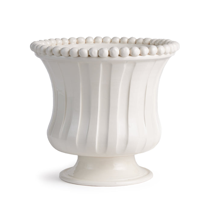White ceramic flared pedestal vase with vertical ribbed grooves and a beaded rim, set against a plain background.