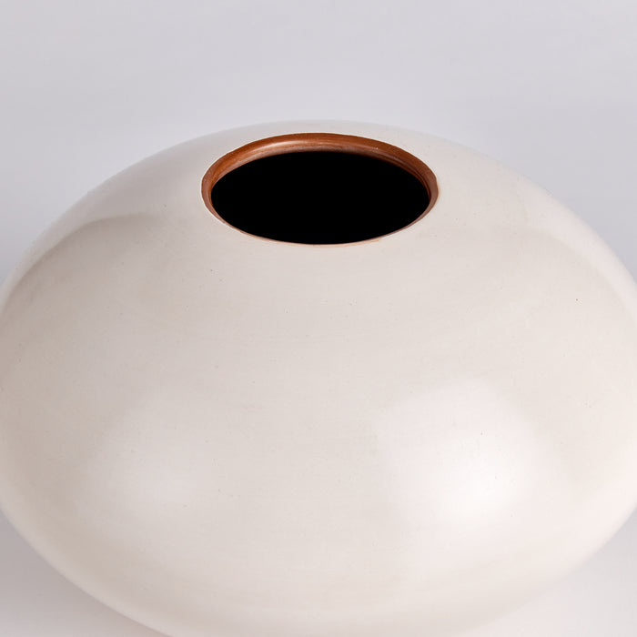 Rounded off-white ceramic vase with a wide dome and a small circular brown rim at a top opening; plain background.