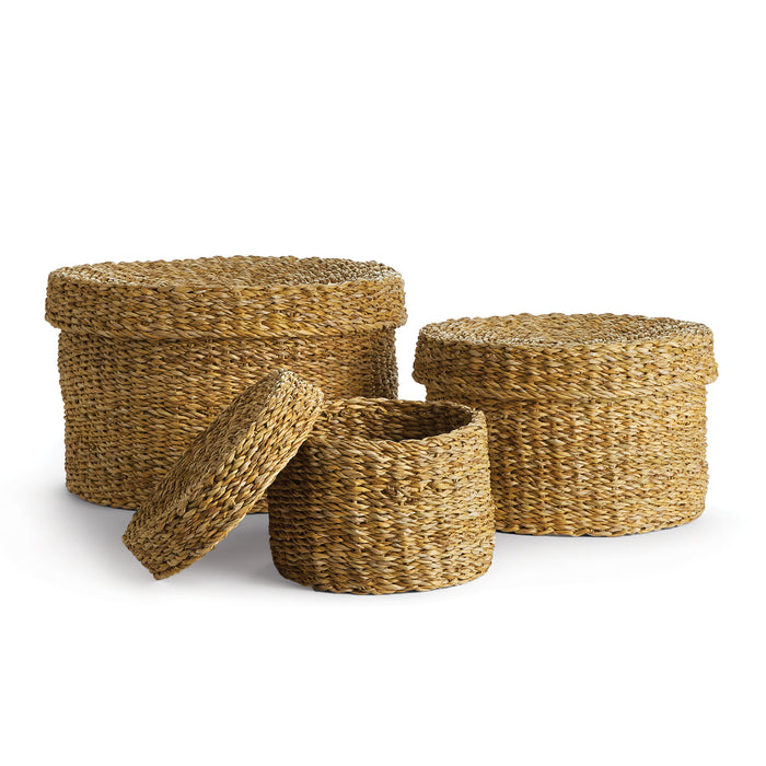 A set of three round lidded baskets made of seagrass, with one basket showing the inside with a lid.