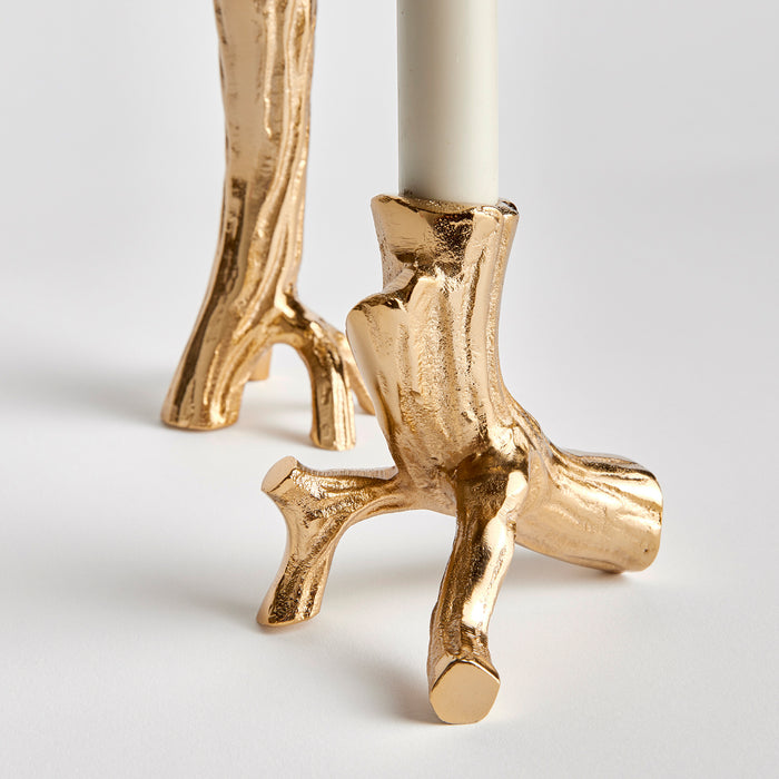 Set of two gold-toned taper candle holders with rough, branch-like textures on ceramic or metal bases, white candles