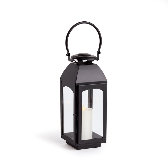 Black metal outdoor lantern with glass panels, curved top handle, candle inside on a white background.