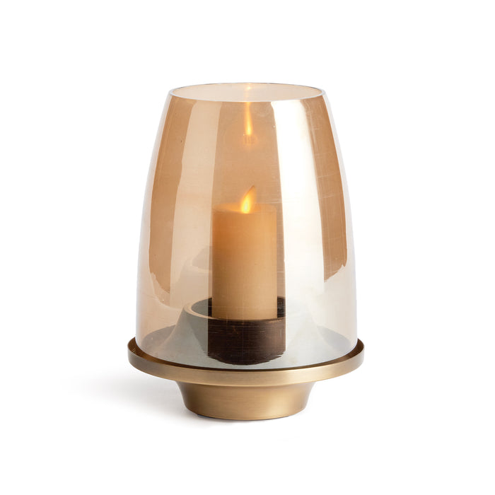 A contemporary style candle holder with a tapered base and a warm luster glass hurricane, finished in matte brass.