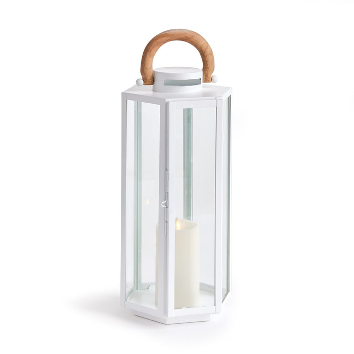 White hexagonal metal lantern with glass panels, wooden top handle, candle inside, minimalist outdoor decor.