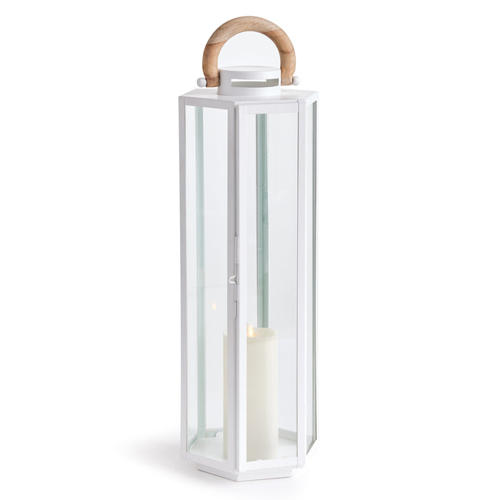 White hexagonal outdoor lantern with glass panels, wooden arched handle, candle inside on white base.
