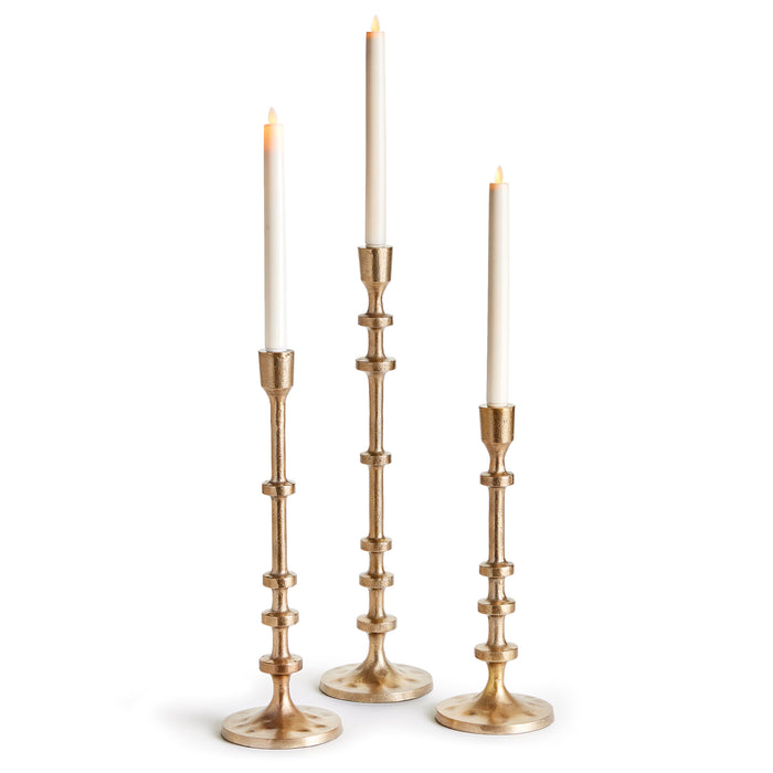 A set of three bronze-colored taper candle holders with notched stems, designed for indoor use.