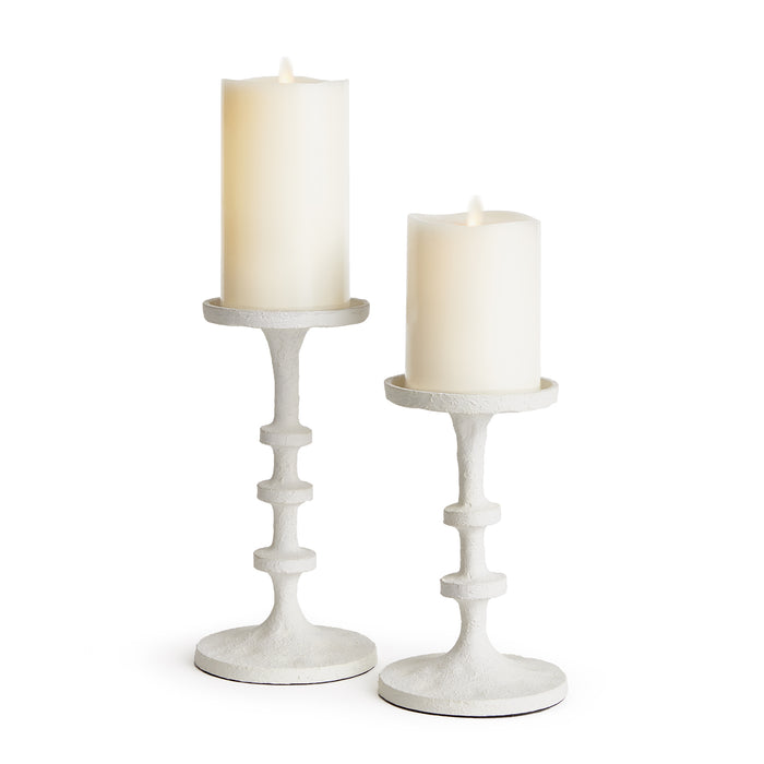 A set of two beige aluminum candle stands with a modern design, each holding a cylindrical white candle.