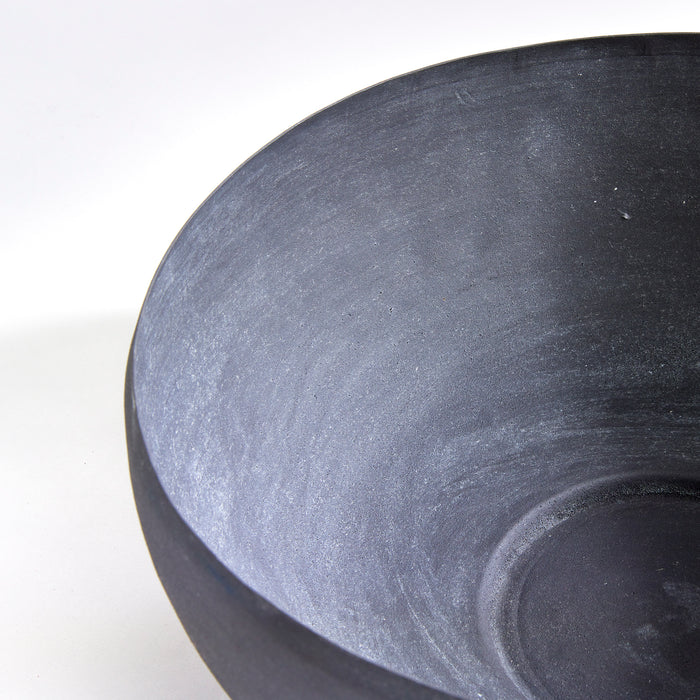 Close-up of a dark gray/blue terrazza decorative bowl interior and rim, showing matte stone-like texture on light background.