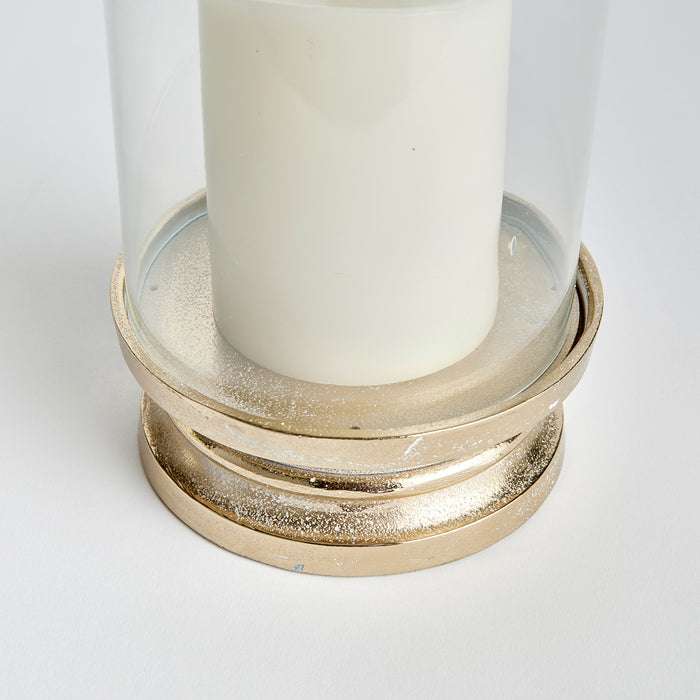 Gold-toned hurricane base with frosted glass cylinder, white candle inside. Surface speckled with white dust on base. Plain