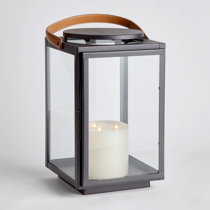 Design Shop Jennings lantern with charcoal metal frame, glass panels, and large white pillar candle inside, leather strap on