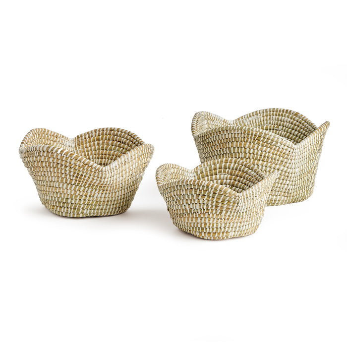 A set of three beige hand-woven Rivergrass Lotus baskets with sculpted petal-like rims.