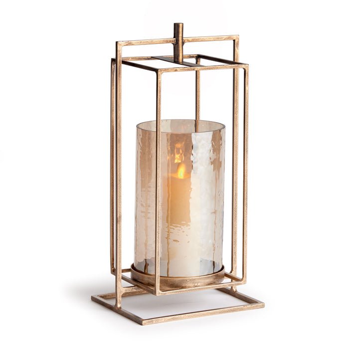 A cylindrical glass hurricane candle holder with a warm antique gold finish and a hammered texture, placed on a square base.