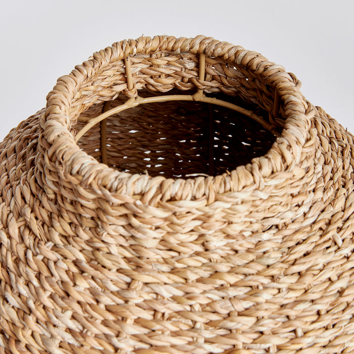 Seagrass round woven basket with wide opening, natural beige tones, thick braided strands, neutral background.