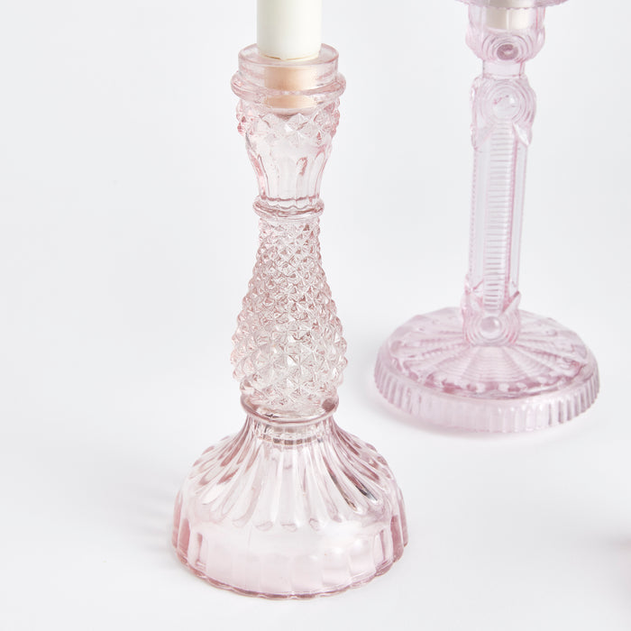 Set of 3 pink cut-glass taper candle holders with diamond-textured stems and ribbed bases on a white background