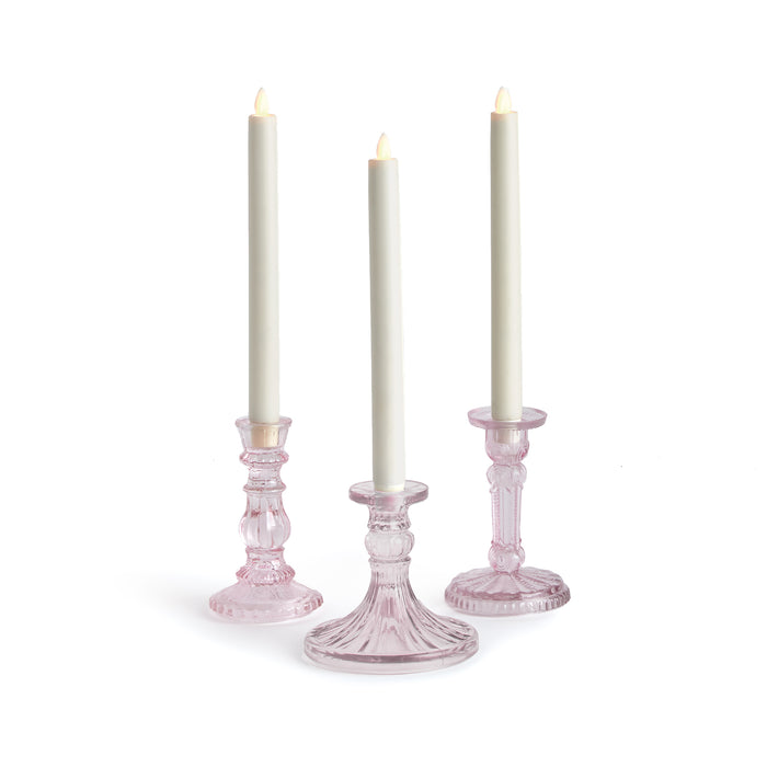 A set of three pink taper candle holders, each with a clear glass base and pink decorative elements.