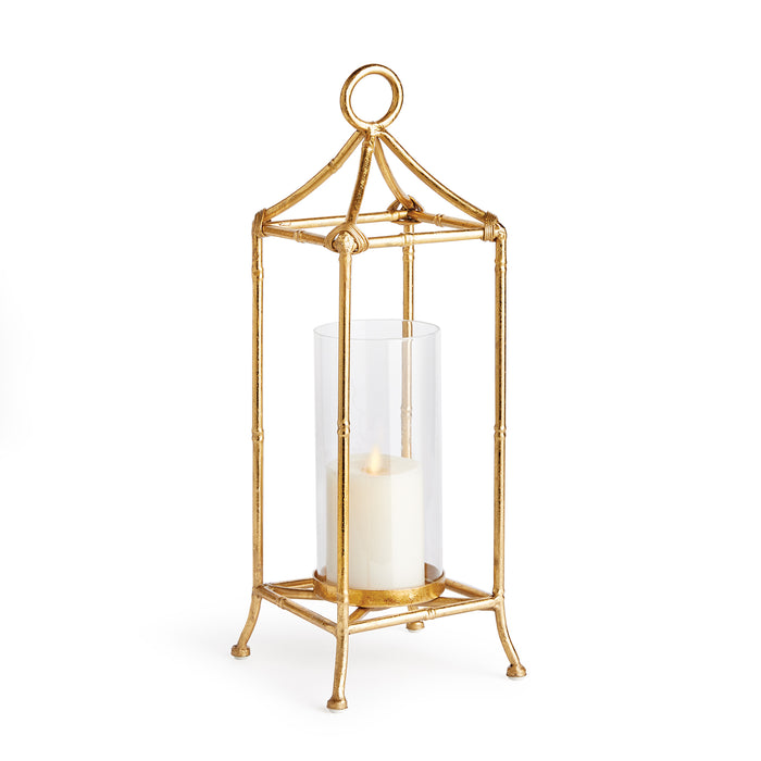 A small antique gold finish lantern with a glass cylinder, designed for holding a candle.