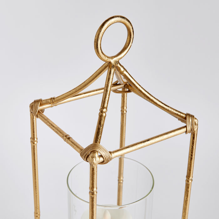 Gold-toned metal lantern frame with a circular loop top, wire-wrapped joints, and a glass cylindrical holder for a candle.
