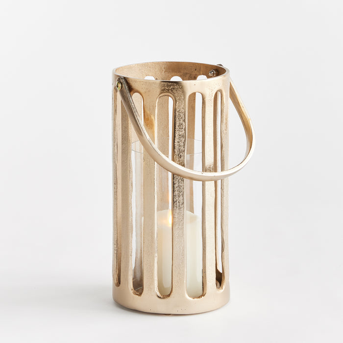 Gold-toned cylindrical lantern with vertical slats, curved handle, and white candle inside, on a white background.