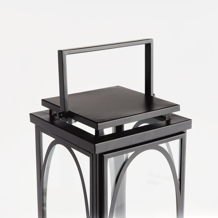 Black metal lantern with glass panels, rectangular top handle, arched frame details, on a white background
