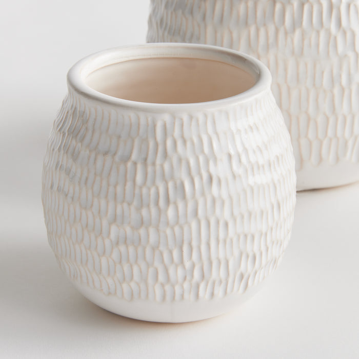 White textured ceramic pots set of 2, round, pebble-like surface, open top, pale pink interior, on light background.