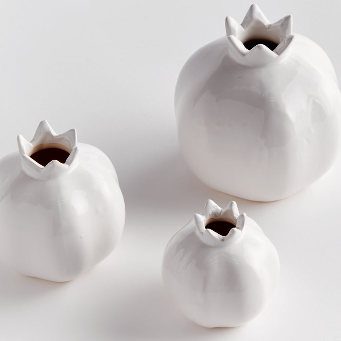 Three white ceramic bud vases of different sizes with jagged, crown-like openings, set on a light background.
