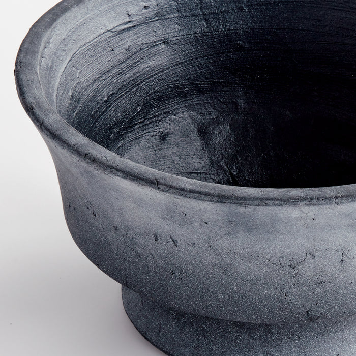 Decorative footed bowl with dark blue-gray, textured ceramic surface and subtle cracks, on light background.