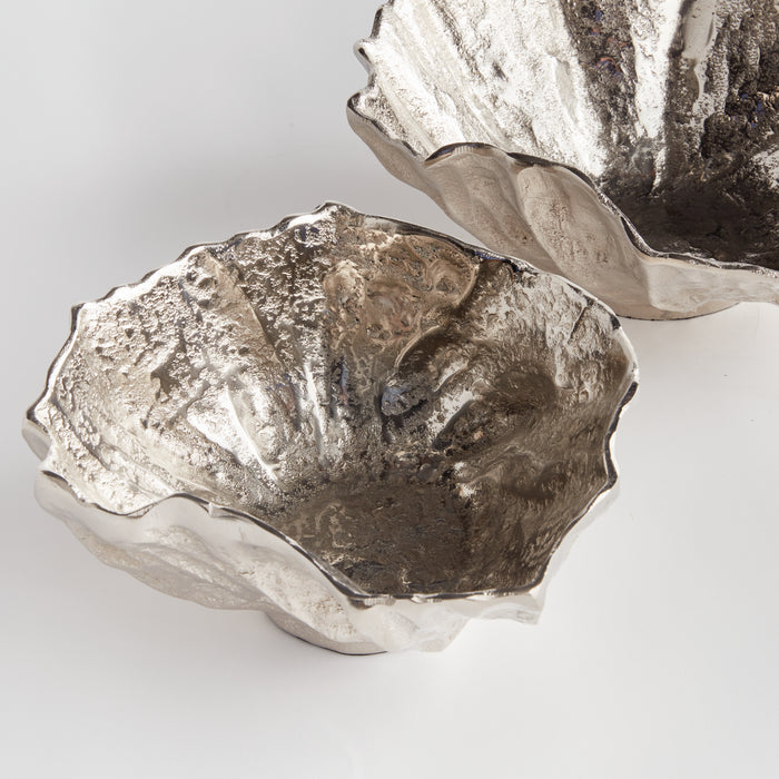 Two metallic decorative bowls with irregular, textured edges, silvery and weathered finish on a light background.