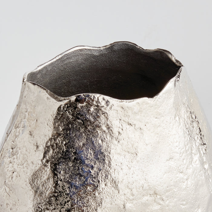 Textured silver vase with a jagged, dark interior rim and irregular surface, whitewashed finish, light gray background.
