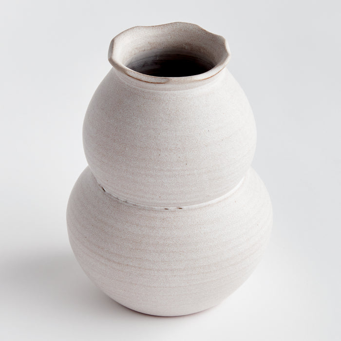 Large white ceramic vase with two stacked bulbous sections and a slightly irregular rim, against a plain light background.