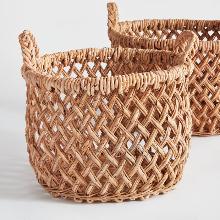 Set of two natural woven baskets with handles, thick braided rim, diagonally lattice weave, on light background