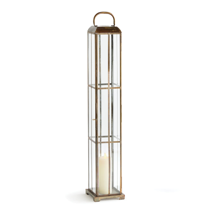 A tall, narrow, brass paneled lantern with a candle inside, designed for indoor use.