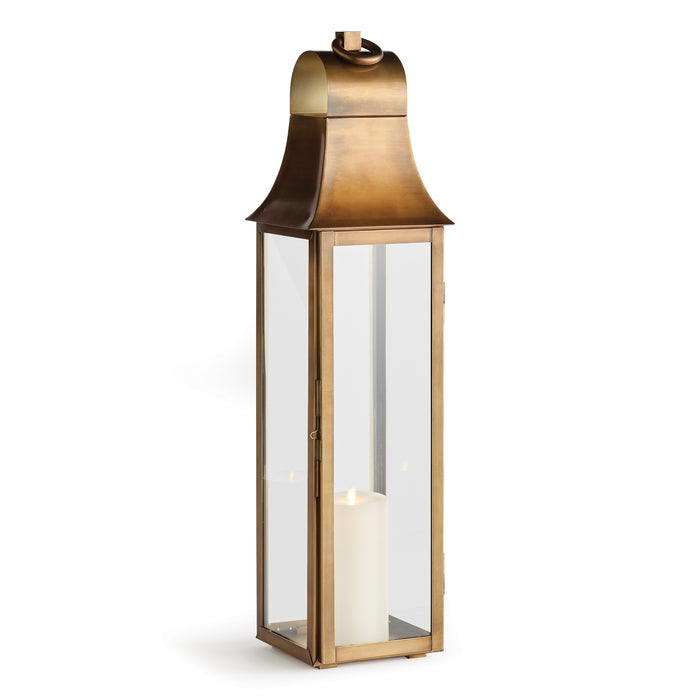 A tall, slender brass lantern with an oversized loop for hanging, featuring a clear glass base and a lit candle inside.