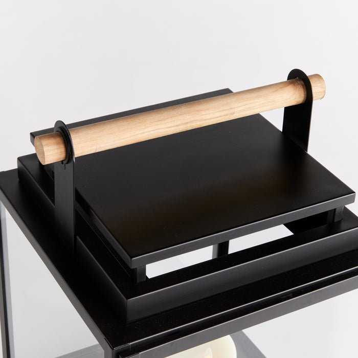 Black metal outdoor lantern with a light wood handle on top and a square flat surface; minimalistic, open frame, neutral
