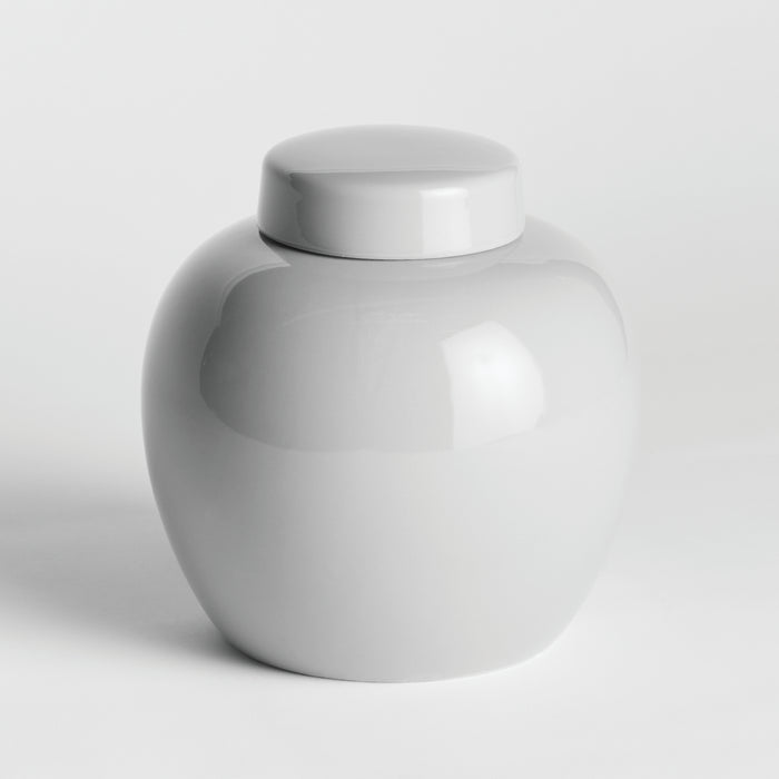 White ceramic lidded jar with smooth, glossy finish and rounded body, plain lid, against a light background.