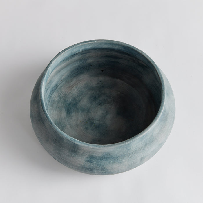 Blue-gray ceramic decorative bowl with matte finish, round open top, no pattern, set on light background.