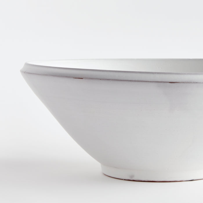 Large white ceramic decorative bowl with a smooth, matte glaze and simple rounded lip, photographed against a light