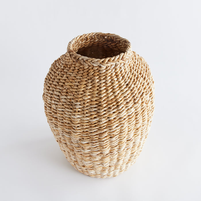 Large natural abaca teardrop vase woven from thick straw, with a rounded body on a light background.