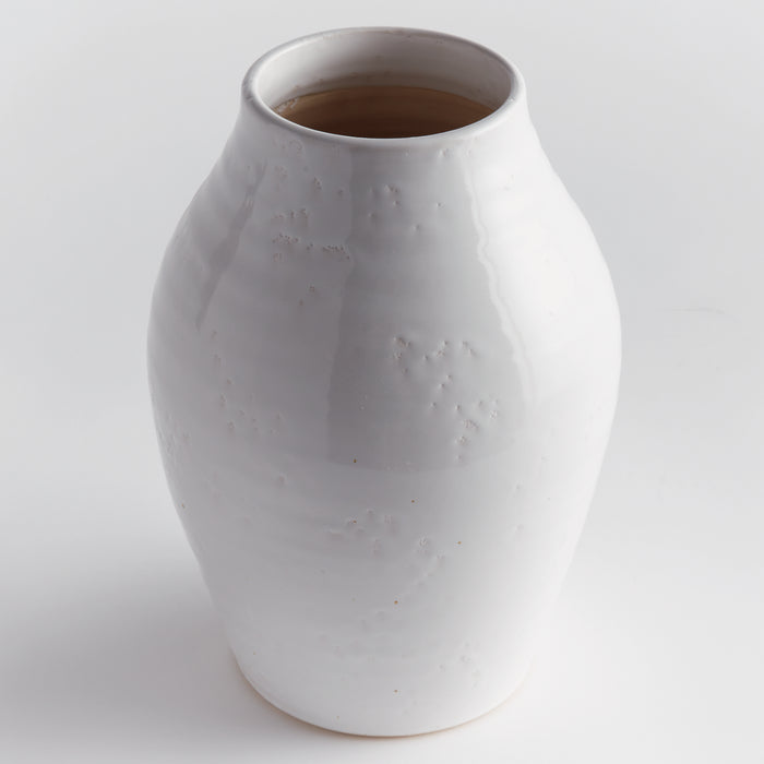 Large white ceramic vase with a glossy, slightly irregular surface and narrow mouth, set against a light background.