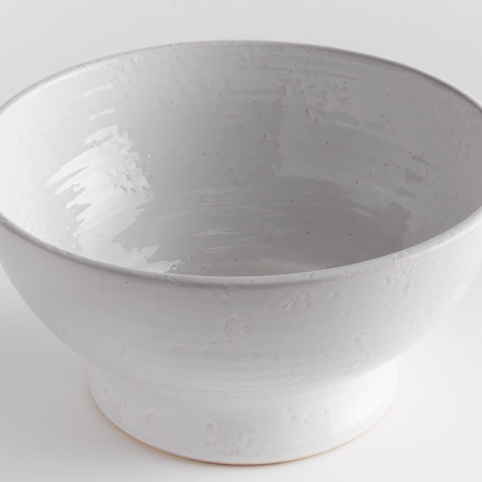 Large white ceramic decorative bowl with a glossy glaze, textured exterior, and a pedestal base against a plain light