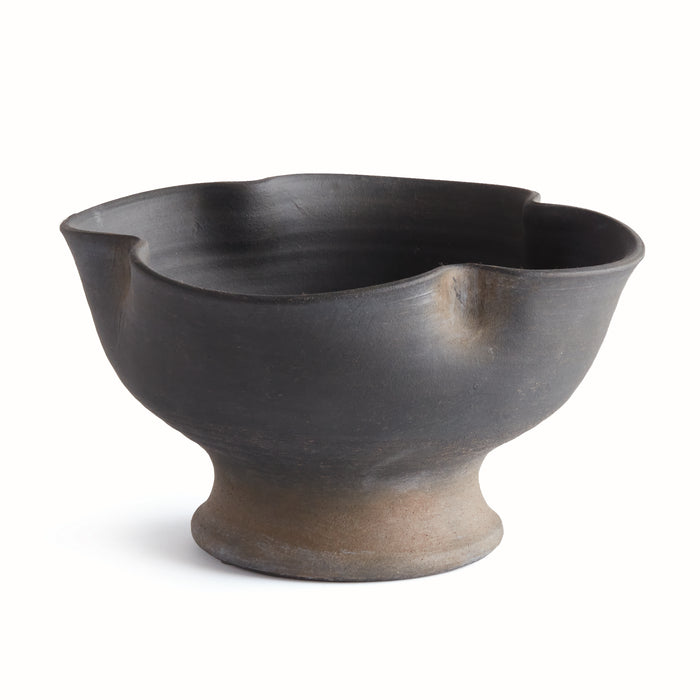 Large dark ceramic bowl with irregular scalloped rim, matte black glaze, lighter stoneware foot, isolated on white.