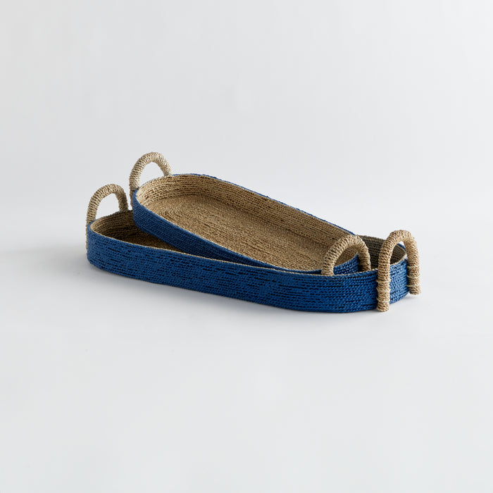 Set of two long oval seagrass baskets with blue exterior, natural interior, and twisted rope handles on ends.