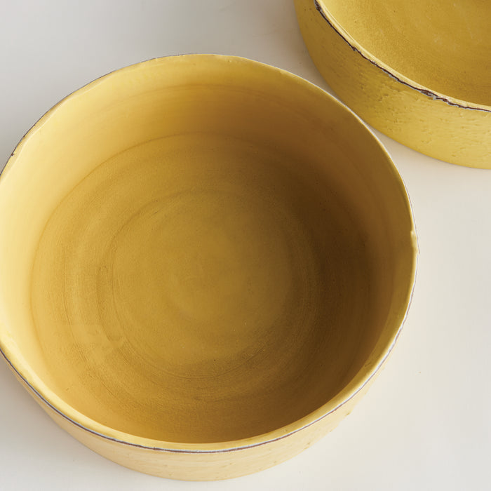 Two round yellow decorative bowls with a matte finish, showing interior and outer edges; light background, subtle shadows.