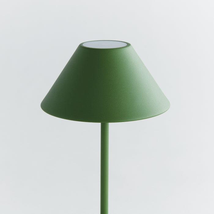 Green cordless LED table lamp with a conical shade on a slim vertical stem against a light gray background.