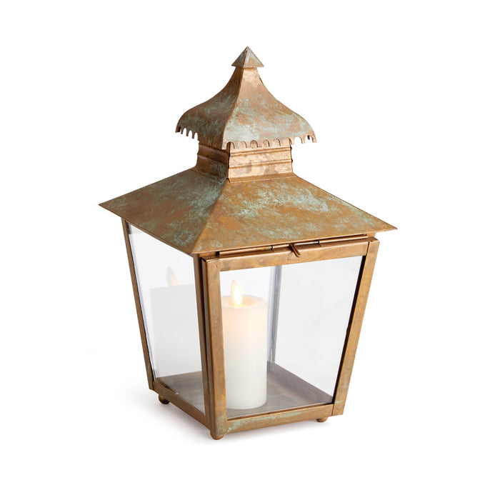 A small iron lantern with a curved pagoda top and notched edge, featuring a warm patina finish and a candle inside.