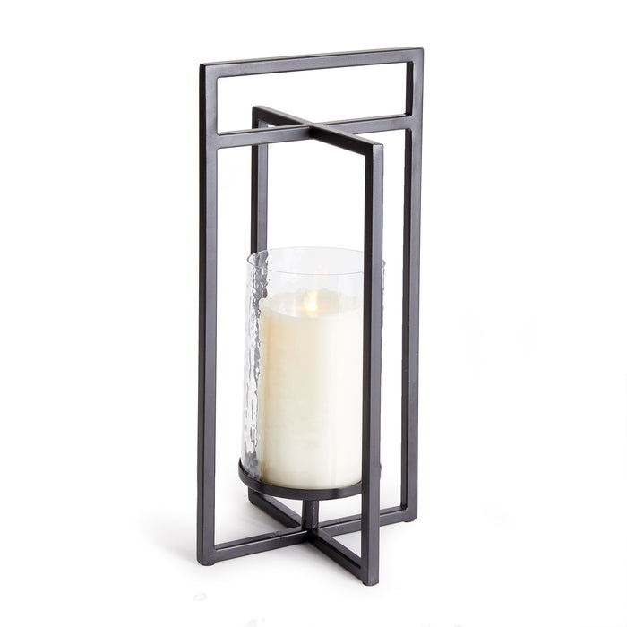 A small indoor lantern with a geometric design, featuring intersecting planes and a candle inside, held by a black iron frame.