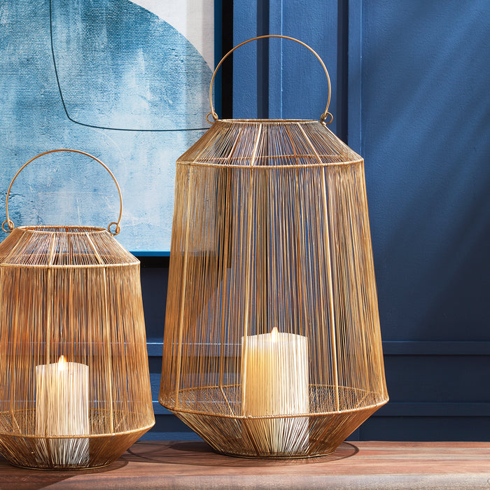 Two gold metal lanterns with wireframe hexagonal bodies, candle inside, round handles, set on a wooden surface against a