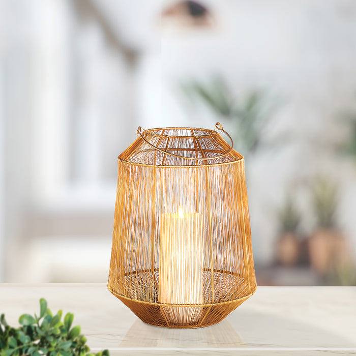 Elwin Lantern Small, warm amber woven rattan lantern with metal handle, lit candle inside, on a light wooden surface with